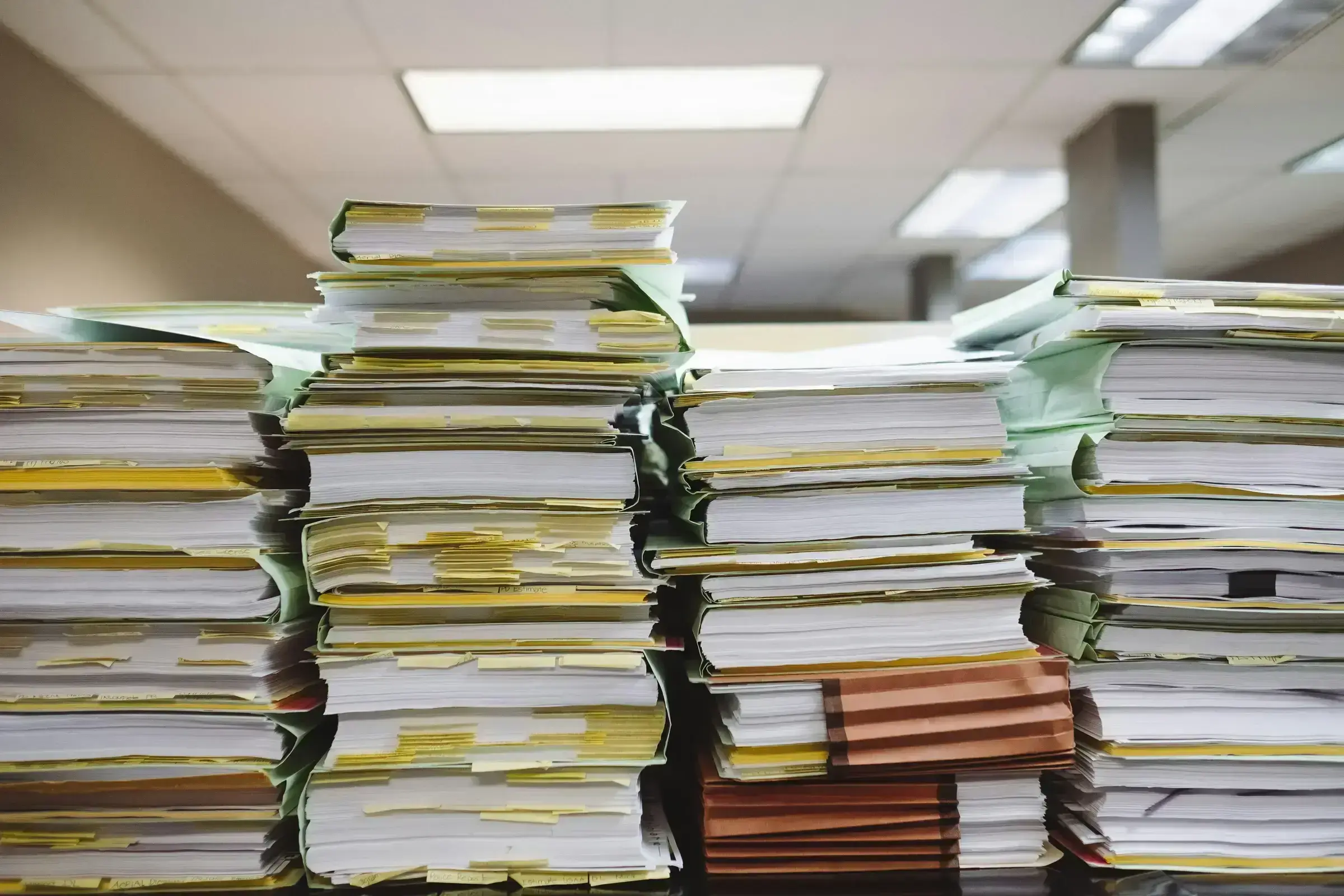 Towering stacks of manilla document folders, a documentary view of the real paperwork involved in a citizenship application.
