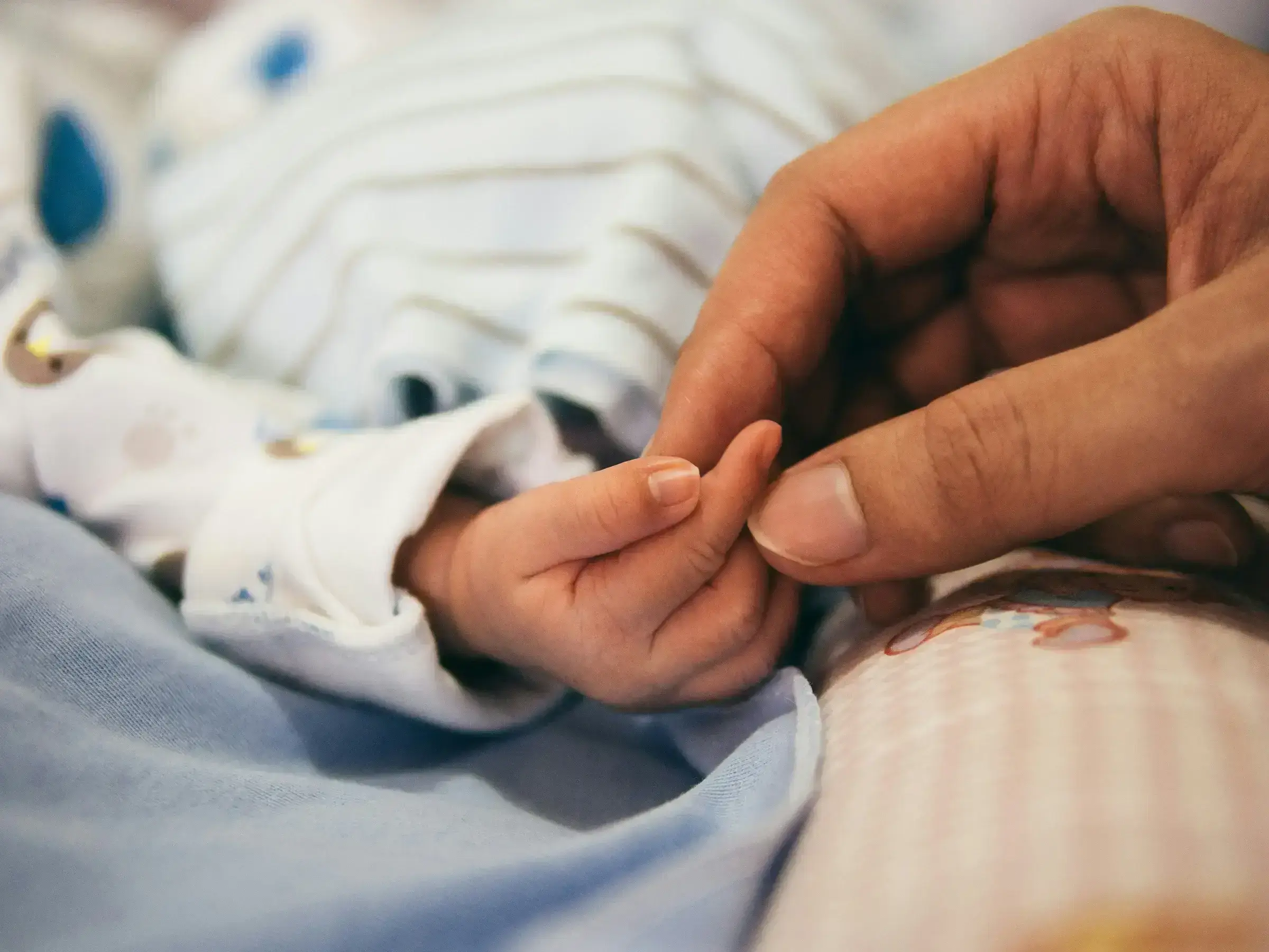 An infant's hand close-up — the smallest scale of family inclusion in a CBI application.