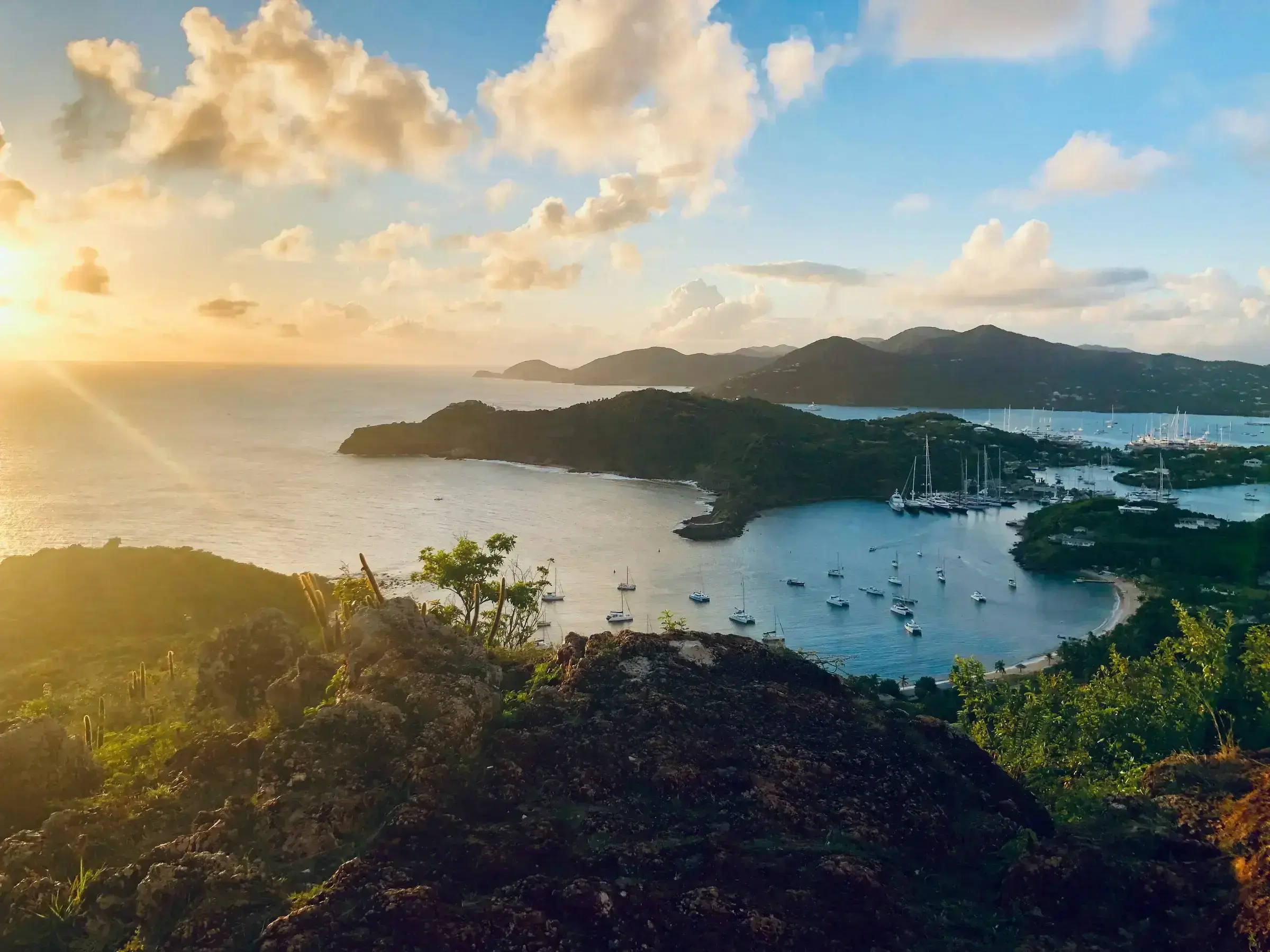 Shirley Heights overlooking English Harbour in Antigua at golden hour, with sailing yachts in the bay below.