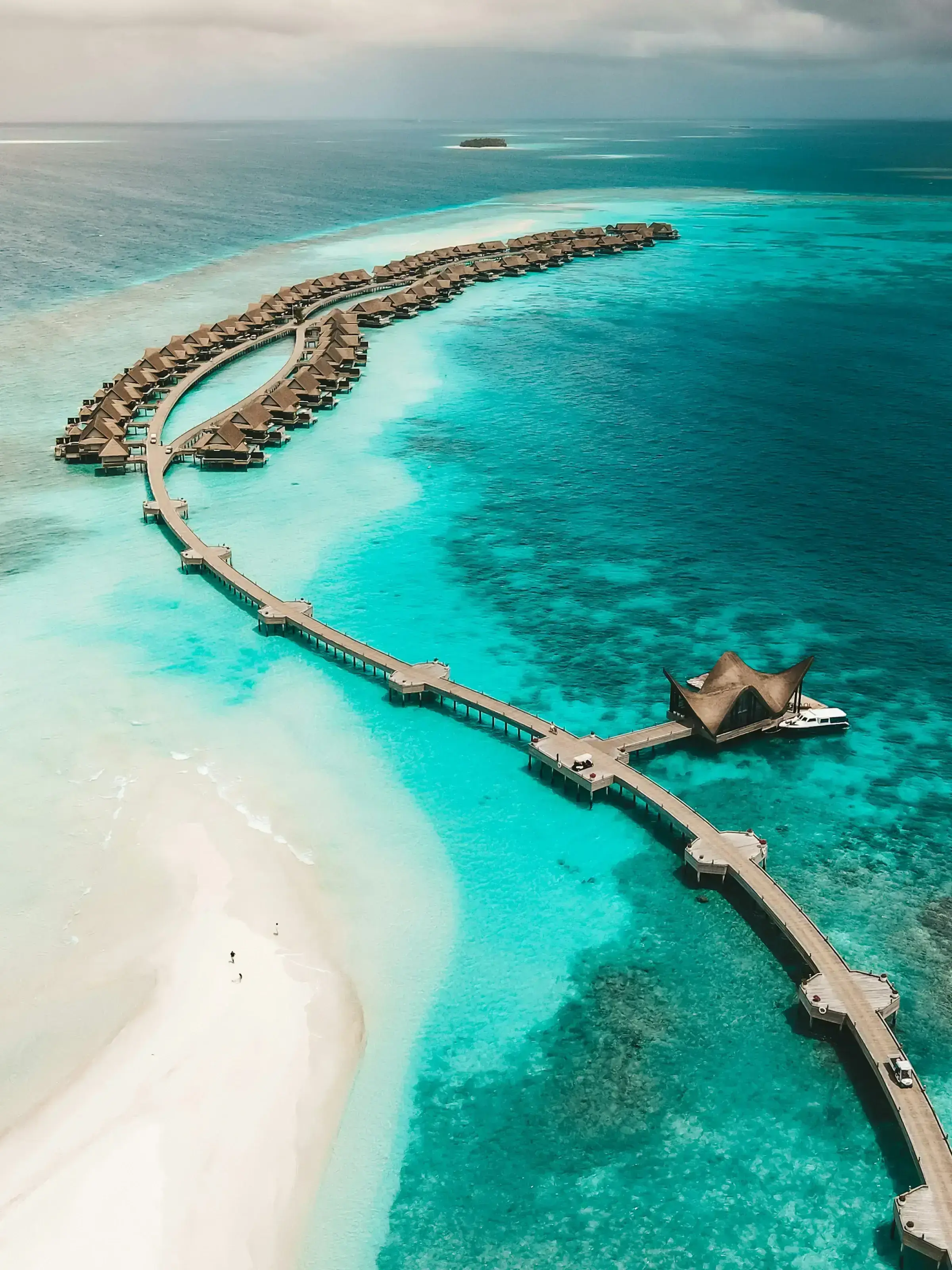 An aerial view of the Maldives' over-water villas against pale turquoise water.