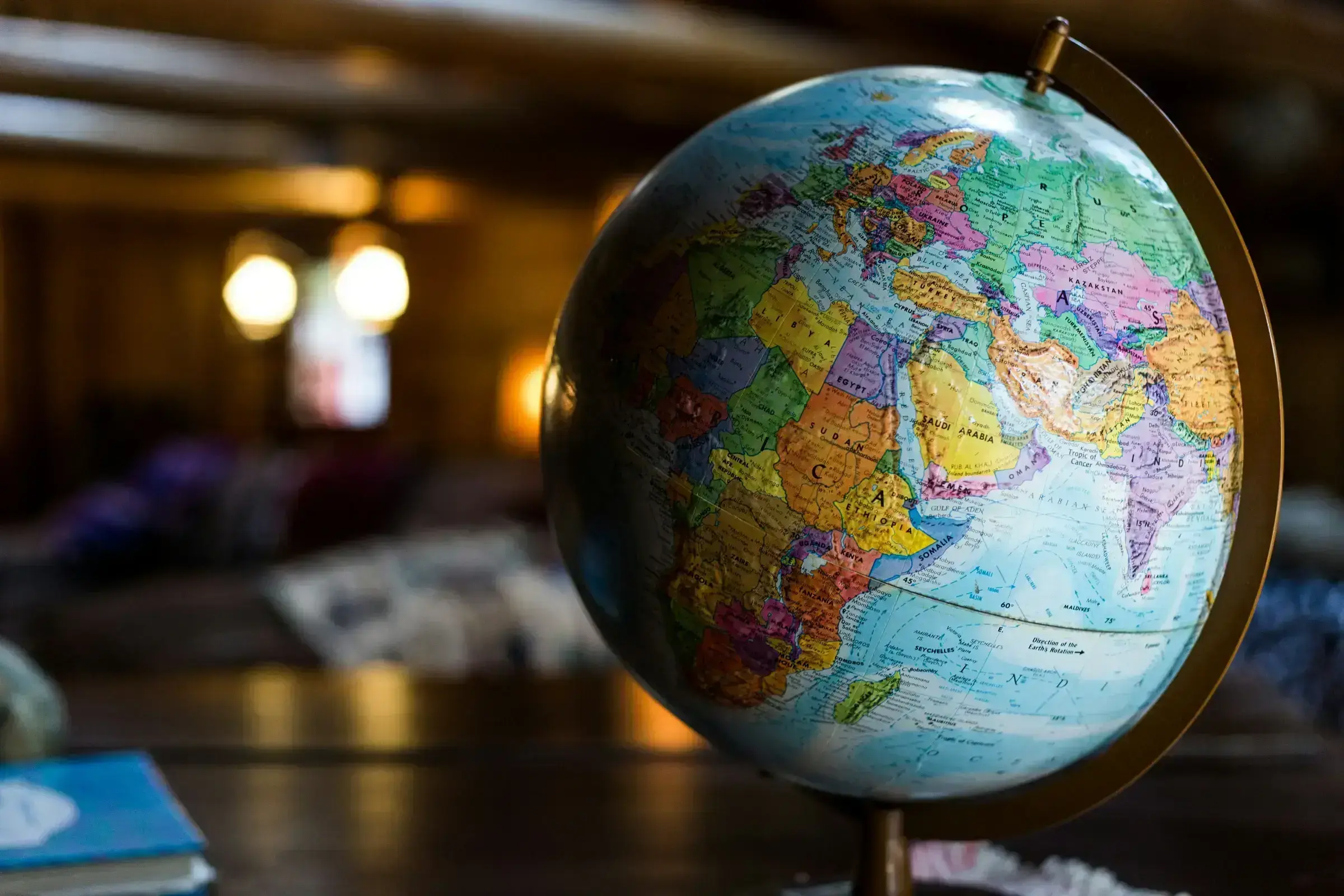 A globe at a quiet angle, set on a polished wooden surface — the natural icon of international mobility.