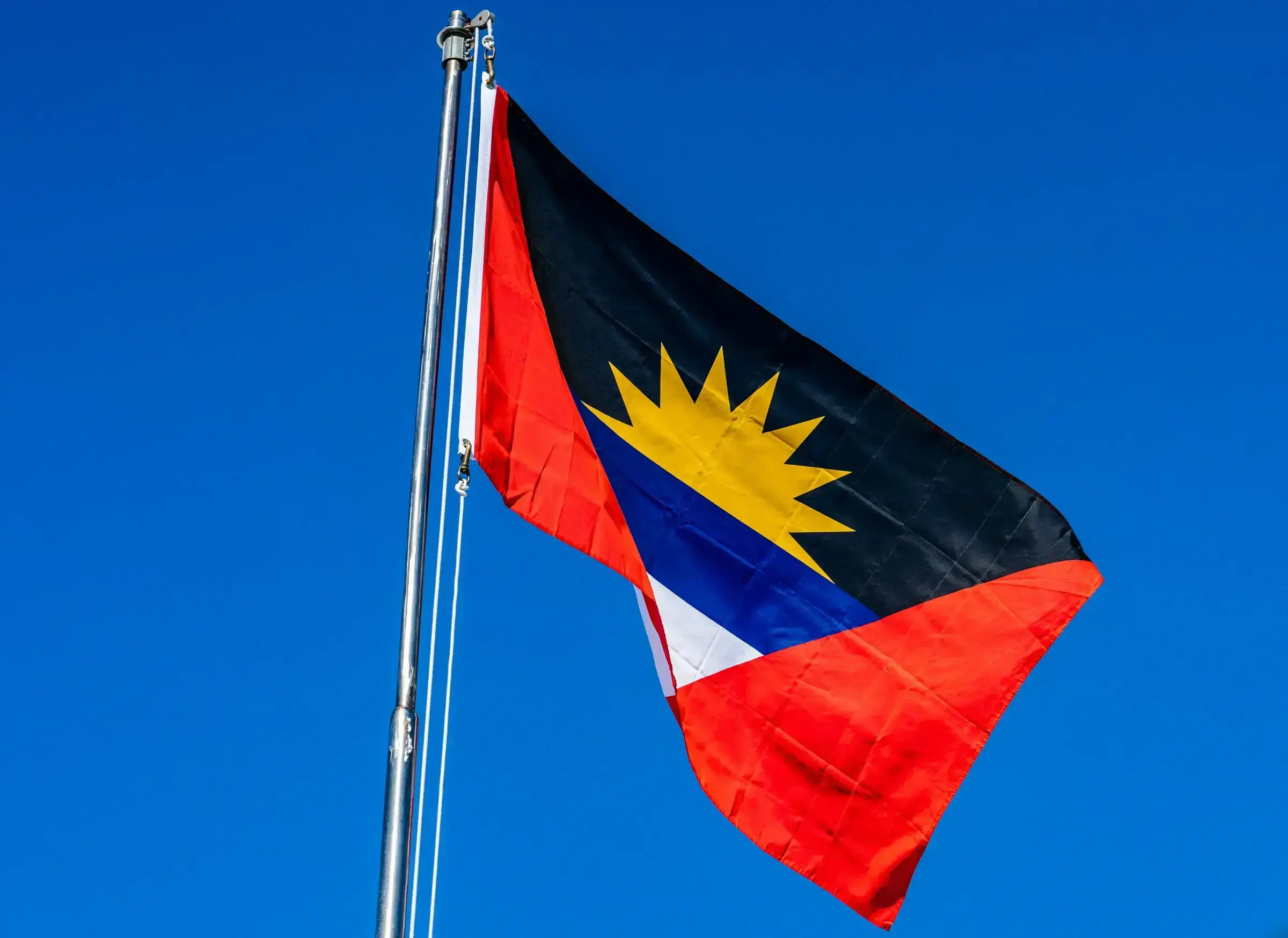 An Antiguan flag detail, the deep red and bright sun emblem clearly visible against the sky.