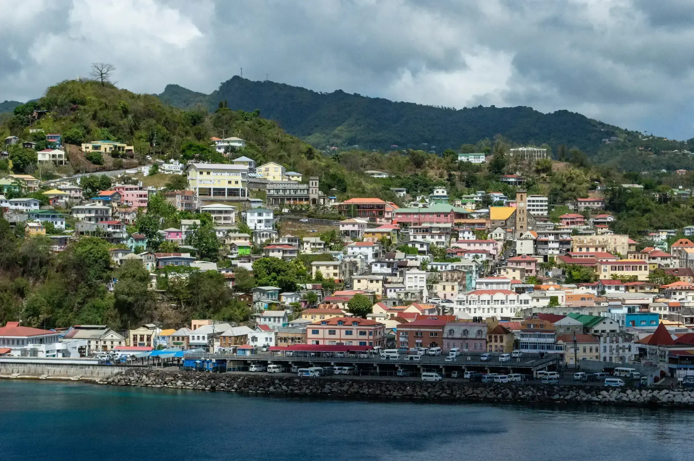 A hillside view of St George's, the colourful capital of Grenada, with painted colonial-era buildings stacked above the harbour.