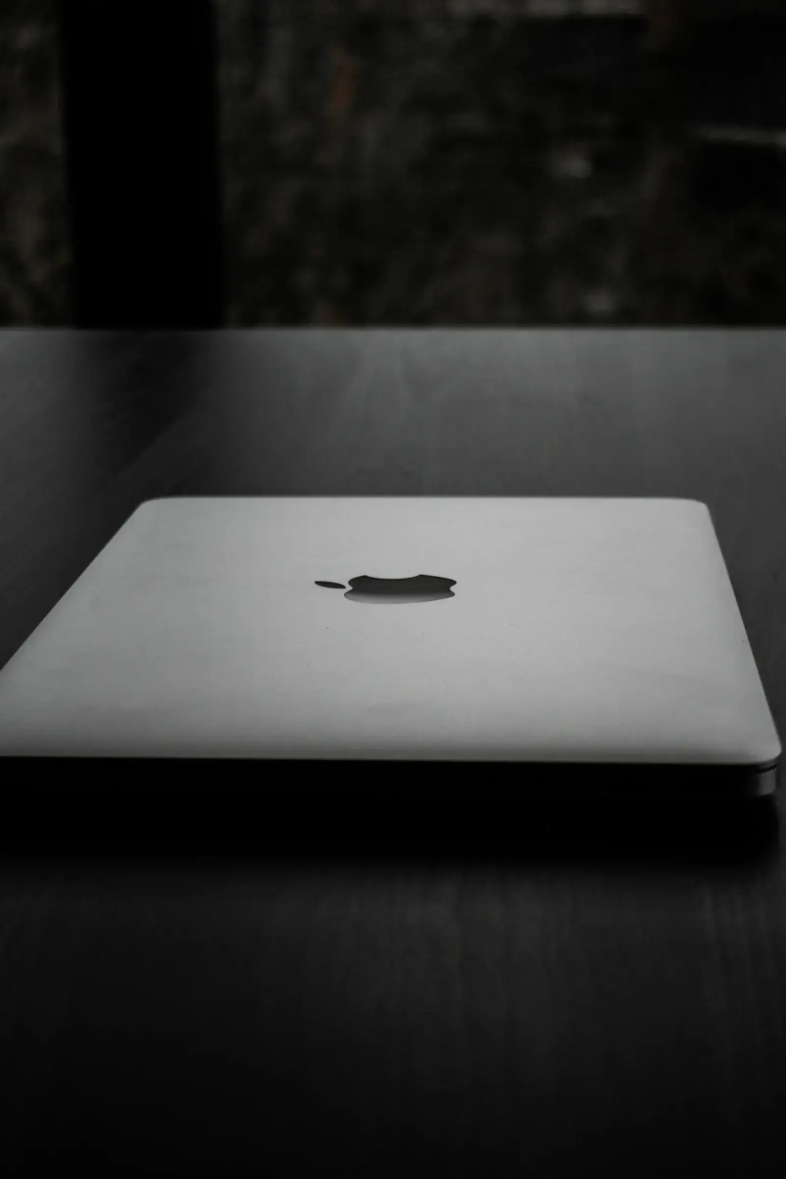 A minimalist laptop on a wood desk displaying an abstract interface — the visual register of the St Kitts and Nevis CIU's new digital platform.