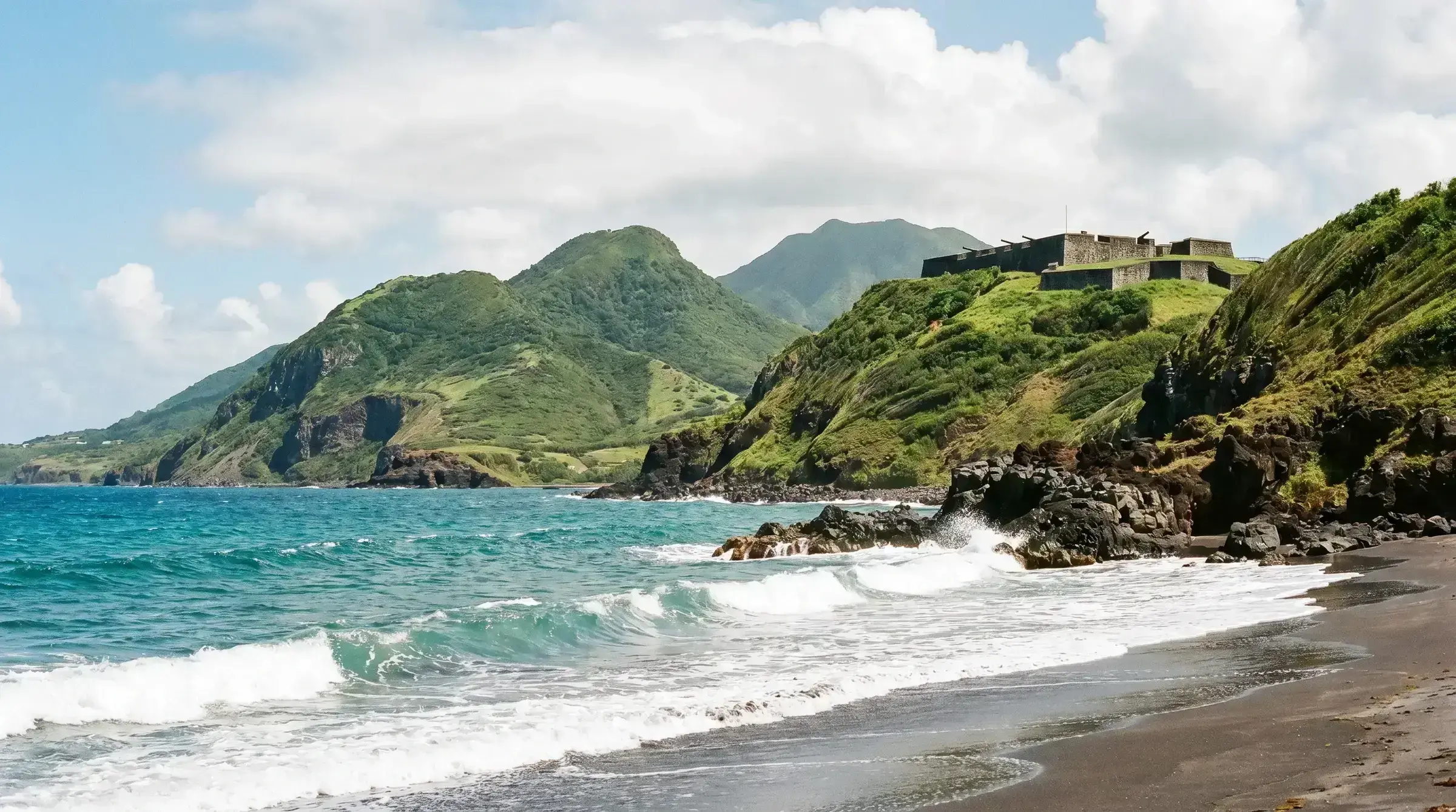 St Kitts and Nevis' coastline with Brimstone Hill Fortress rising on the hilltop — a UNESCO-listed landmark and a recognisable national image.