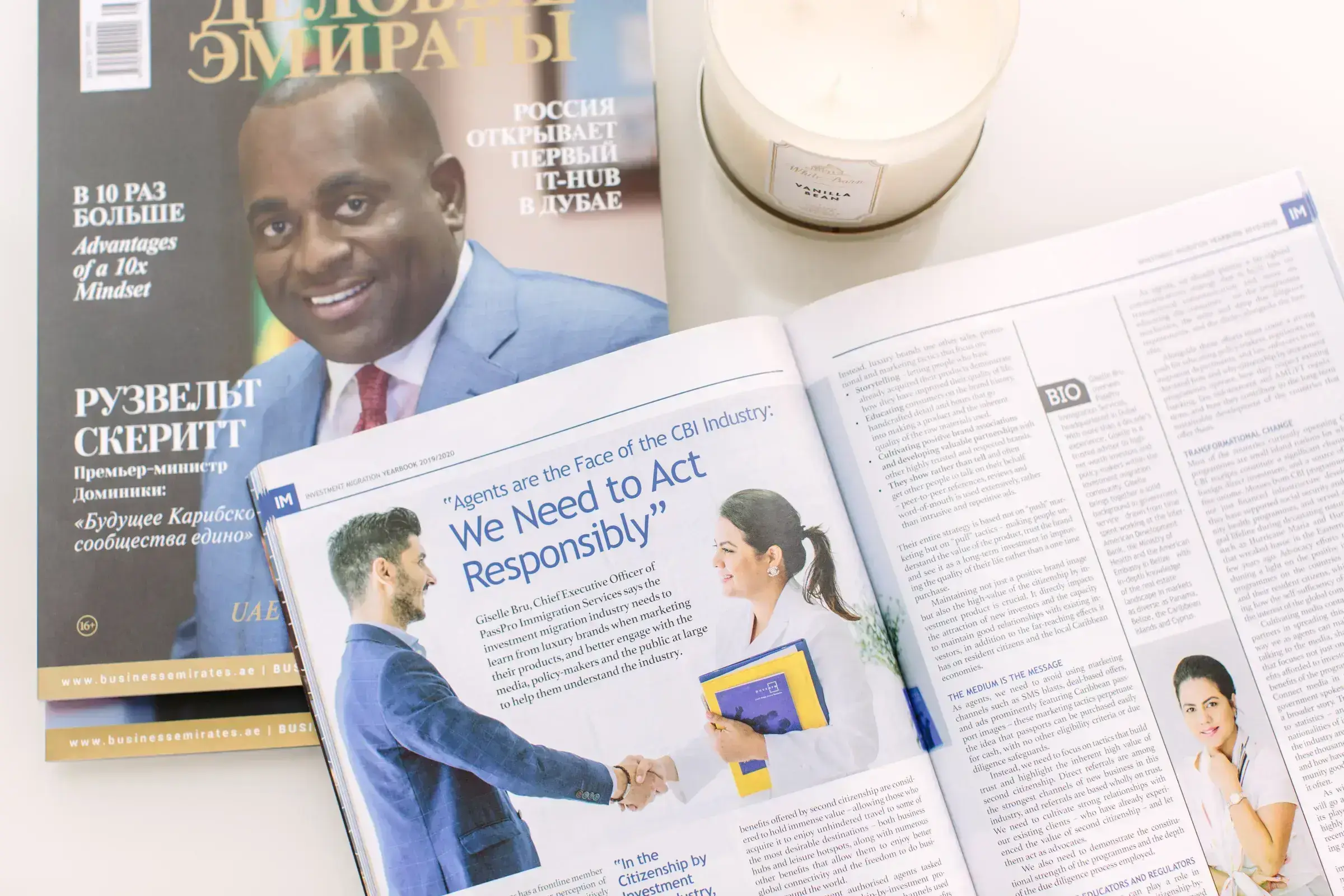 A Business Emirates magazine featuring PassPro and an editorial spread on Citizenship by Investment, beside a candle.